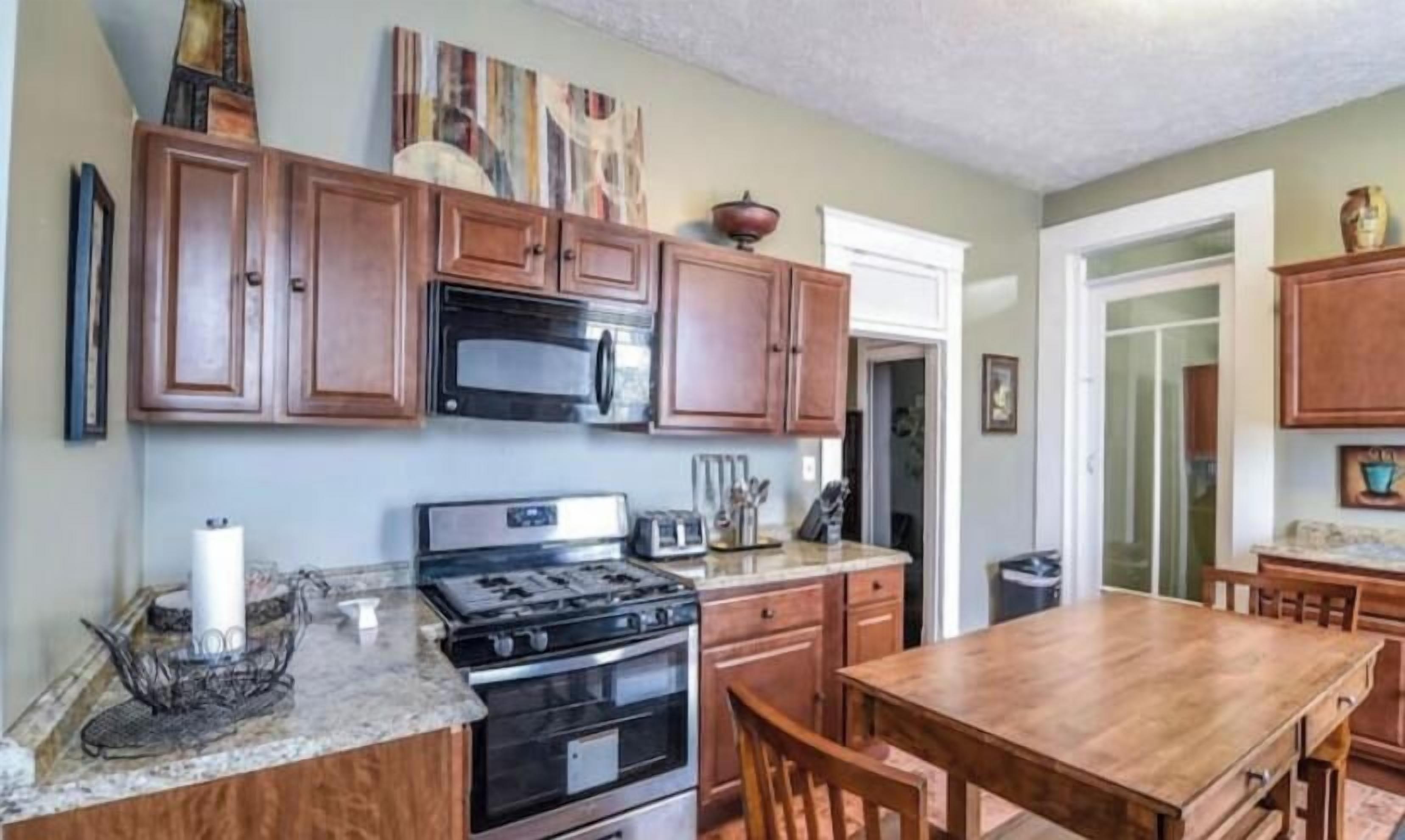 Une cuisine avec des meubles de rangement en bois, une cuisinière et une table à manger.