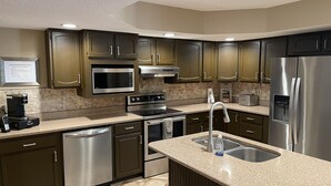 Una cocina moderna con electrodomésticos de acero inoxidable, encimeras de granito y armarios de madera.
