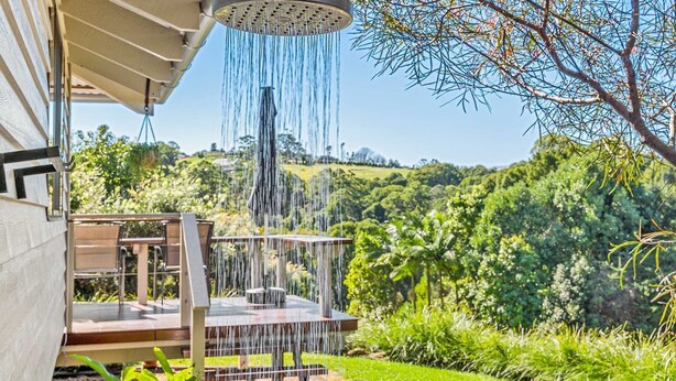 Une terrasse agrémentée d’un élément aquatique, entourée d’une végétation luxuriante et offrant une vue sur un paysage vallonné.