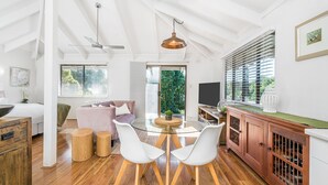 Une cuisine moderne avec une table ronde en verre, des chaises blanches et un meuble en bois contenant des bouteilles de vin.