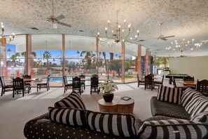 Relax in a spacious lounge area with comfortable seating and a stunning view of the outdoor pool and palm trees.