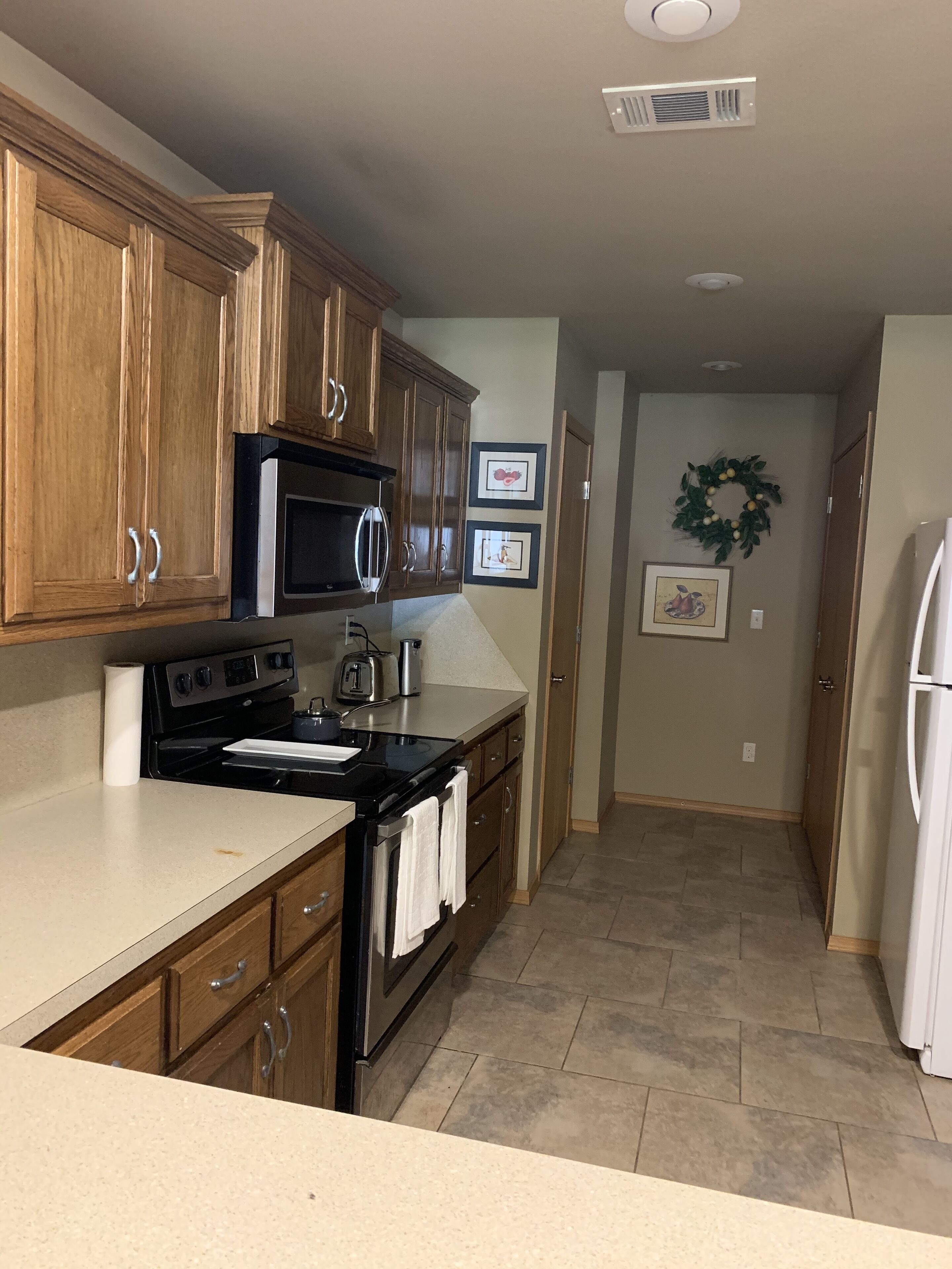 A kitchen with wooden cabinets, a stove, a microwave, and a refrigerator.