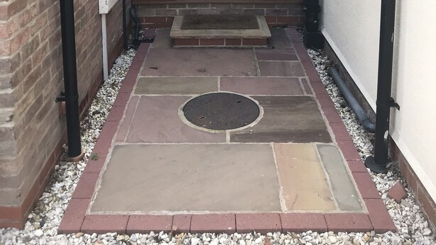 A brick exterior with a wooden door, a small step leading to the entrance, and a man standing in the doorway. - Luxury Private Apartment (Lincoln)
