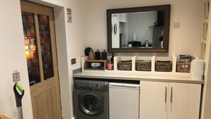 A compact kitchen with a washing machine, dishwasher, and a mirror above the counter. - Luxury Private Apartment (Lincoln)