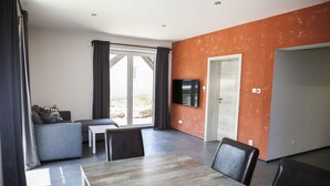Een moderne woonkamer met een bank, eettafel en stoelen.