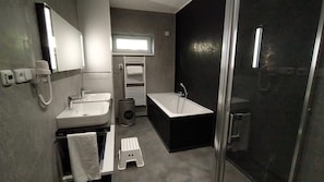 Un baño moderno con lavamanos, espejo y cabina de ducha.