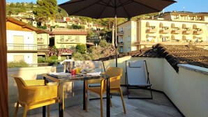 A terrace with a table, chairs, and an umbrella. - LA TERRAZZA CON VISTA (Torri del Benaco)
