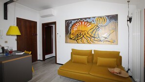 A modern living room with a mustard sofa, a yellow lamp, and a large abstract painting on the wall. - LA TERRAZZA CON VISTA (Torri del Benaco)