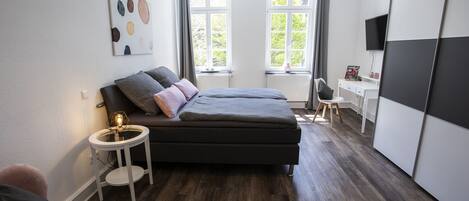 A modern bedroom with a bed, bedside table, and a TV.