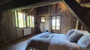 A wooden room with a bed, windows, and a radiator. - Beautiful chalet, private garden, hot-tub, 2 minutes' walk to Samoens centre (Samoëns)