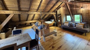 A rustic wooden interior with a loft bed, a sofa, a dining table, and a swing. - Beautiful chalet, private garden, hot-tub, 2 minutes' walk to Samoens centre (Samoëns)