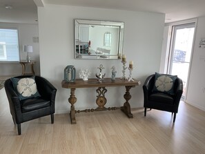 Een kamer met een houten tafel, twee zwarte lederen stoelen, een spiegel en een raam.