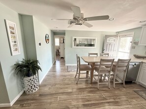 A kitchen with a dining area, a ceiling fan, and a potted plant.