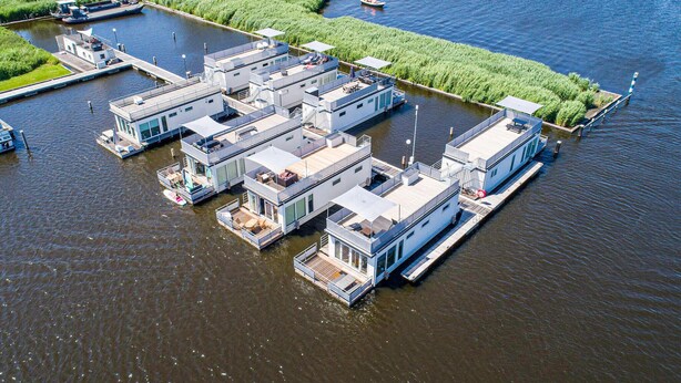 A floating complex with multiple interconnected buildings, docked boats, and a narrow waterway.