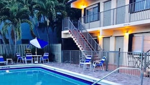 A swimming pool with lounge chairs and a staircase leading to an upper level. - Petrina Apartments (Pompano Beach)