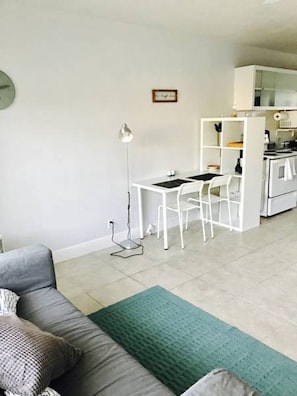 Ett kompakt bostadsutrymme med ett litet kök, en matplats och en soffa.