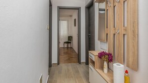 Ein Flur mit Holzboden, einem Sessel, einem Spiegel und einer Vase mit Blumen.