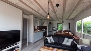 Un salon moderne avec un canapé en cuir noir, une table basse en bois et un téléviseur à écran plat.