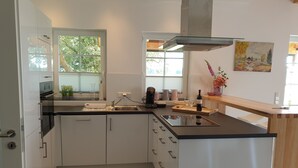 Une cuisine moderne avec des meubles blancs, un plan de travail noir et une fenêtre donnant sur un paysage verdoyant.