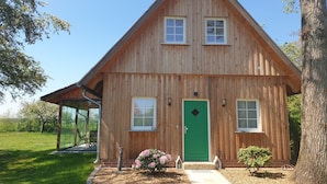 Une cabane en bois avec une porte verte, deux fenêtres et un petit porche.