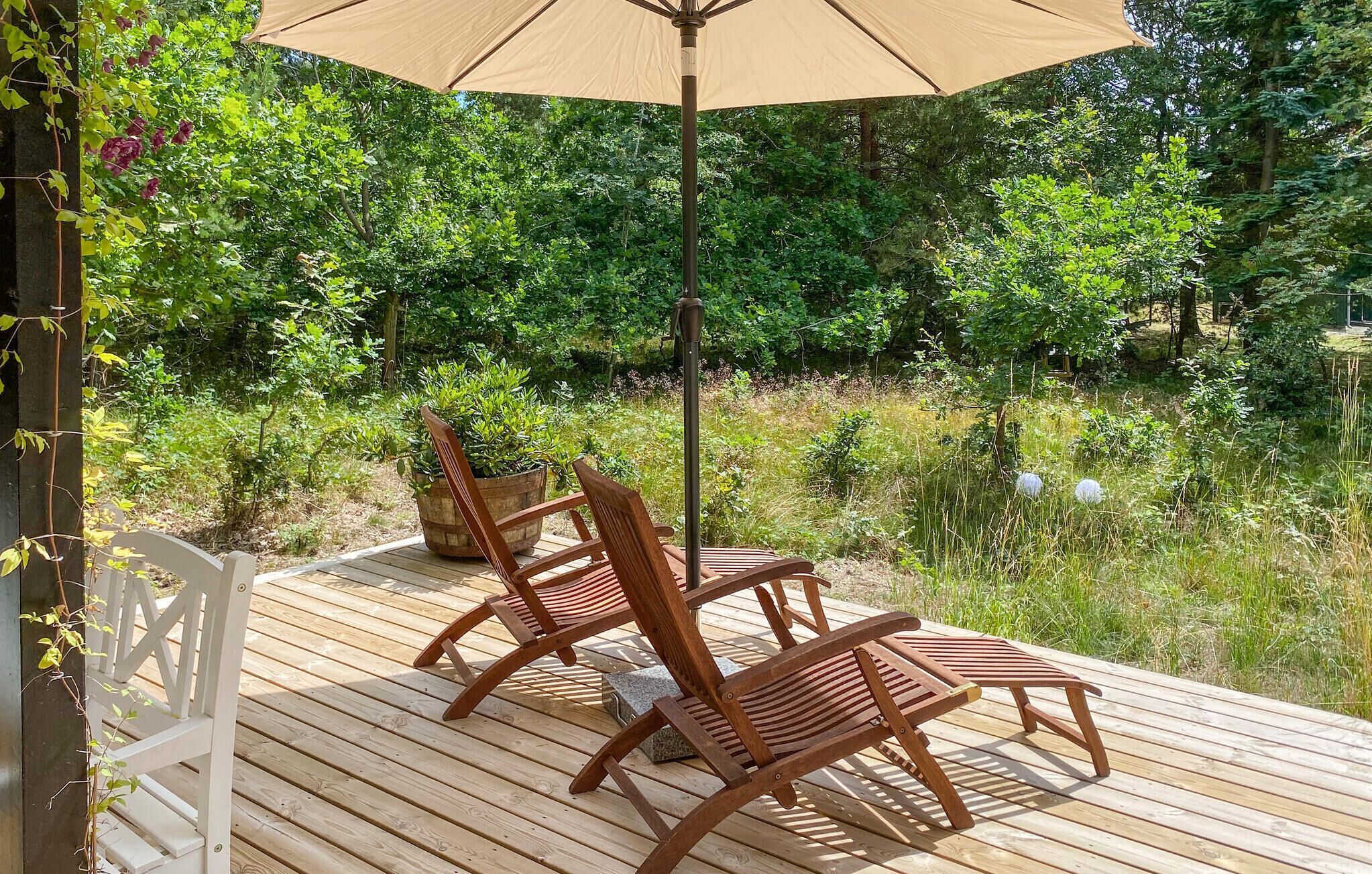 A wooden deck with two wooden chairs and a beige umbrella.