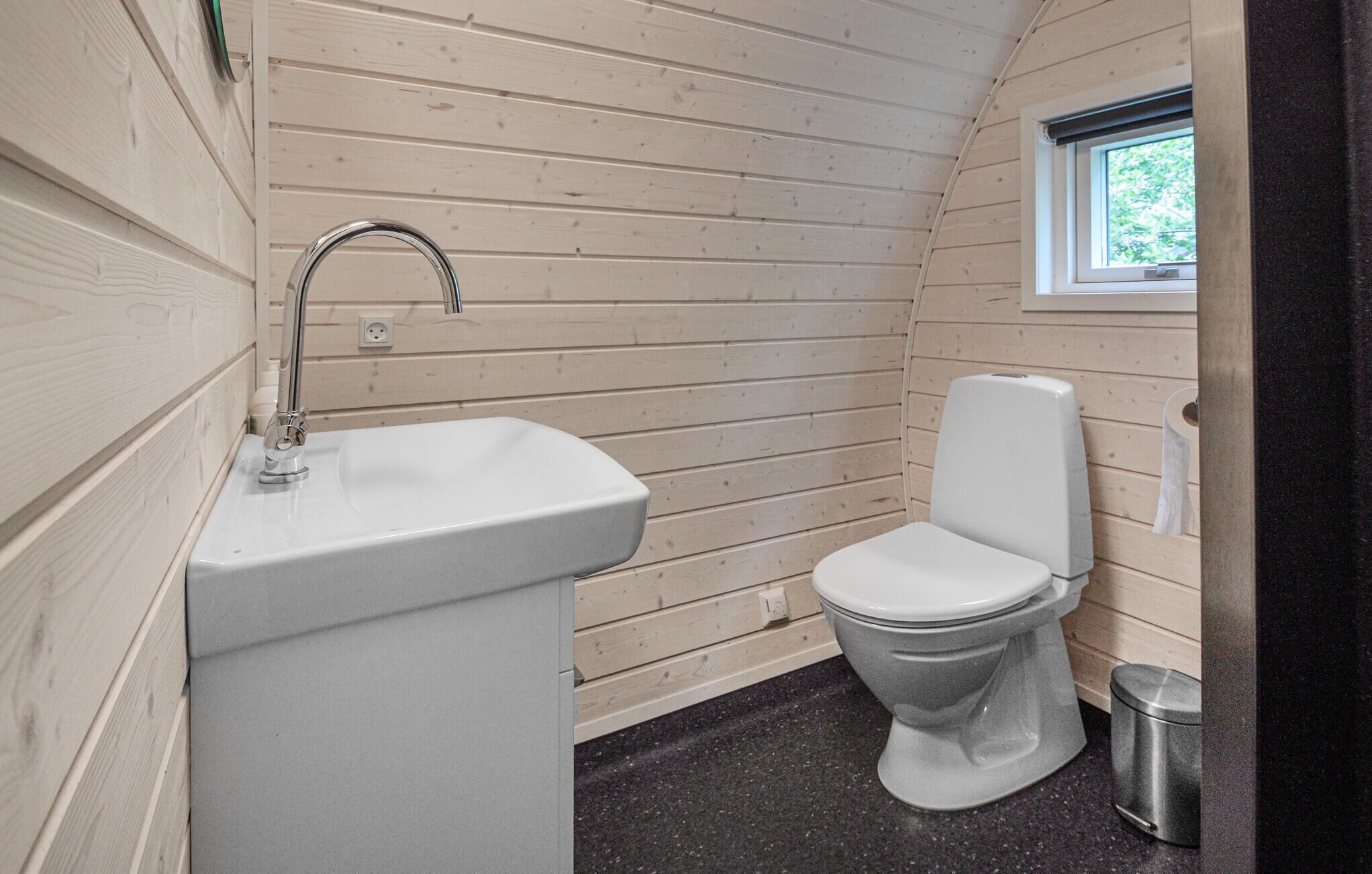 A small bathroom with a white sink, a toilet, and a window.