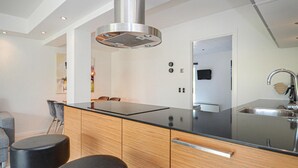 Et moderne køkken med en central ø, rustfrie apparater og et minimalistisk design.