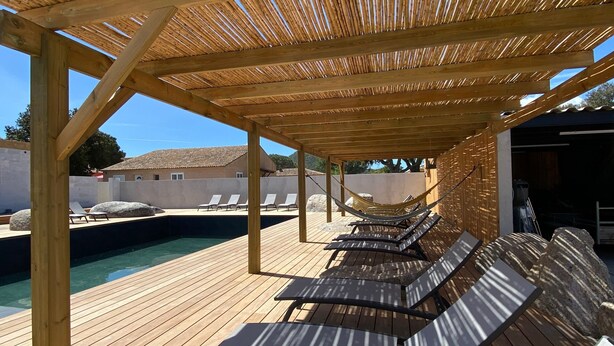 Um deck de madeira com espreguiçadeiras e uma piscina.