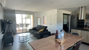 Cozinha moderna com mesa de jantar de madeira, cadeiras pretas e forno embutido.