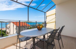 Enjoy a seaside view from this balcony with a table and chairs, overlooking the ocean and a nearby building.