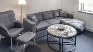 A modern living room with a grey sofa, a matching armchair, a small ottoman, and a round coffee table with a vintage design. - Gorgeous apartment in Rødekro with WiFi (Rødekro)