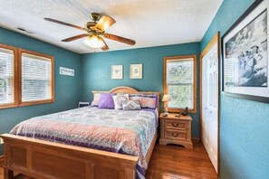 Une chambre à coucher avec un lit, une table de chevet et un ventilateur de plafond.