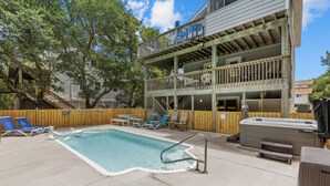 Ein Poolbereich mit Liegestühlen, einem Whirlpool und einer Holzterrasse mit Geländer.