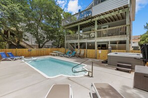 A pool area with lounge chairs, a hot tub, and a wooden deck with a railing. - Corolla Beach Retreat with a Pool! (Corolla)