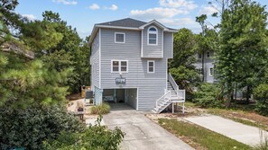 A two-story house with a covered front porch and a staircase leading to the second floor. - Corolla Beach Retreat with a Pool! (Corolla)