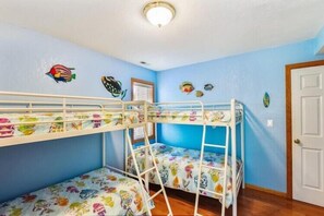 A room with bunk beds, a door, and wall decorations. - Corolla Beach Retreat with a Pool! (Corolla)