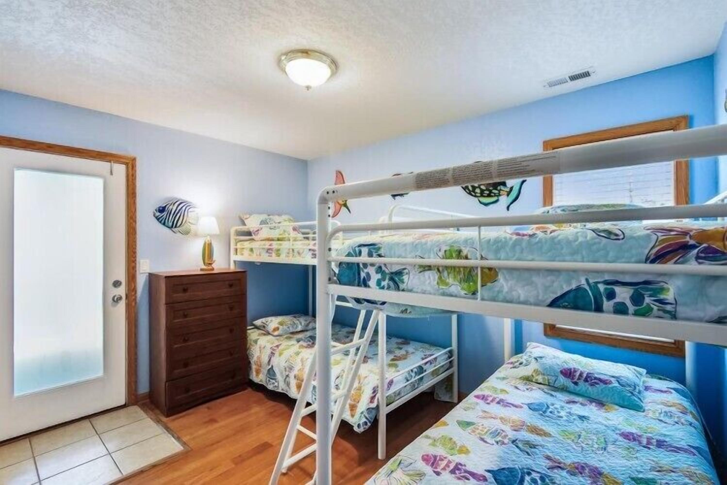 A room with bunk beds, a dresser, and a door.