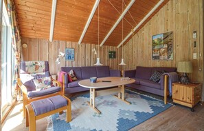 Relax in a spacious room with a seating area, featuring a sofa, armchairs, and a cabinet with a lamp.