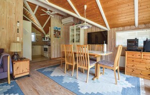 Cozy room with a dining area, television, and kitchenette, featuring wooden walls and floors.