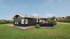 A single-story black building with a sloped roof, a small porch, and a paved entrance.