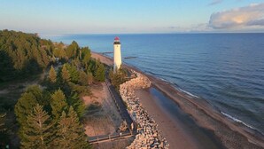 A lighthouse by a rocky shoreline with a forested area in the background.