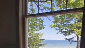 A room with a window overlooking a body of water and trees.