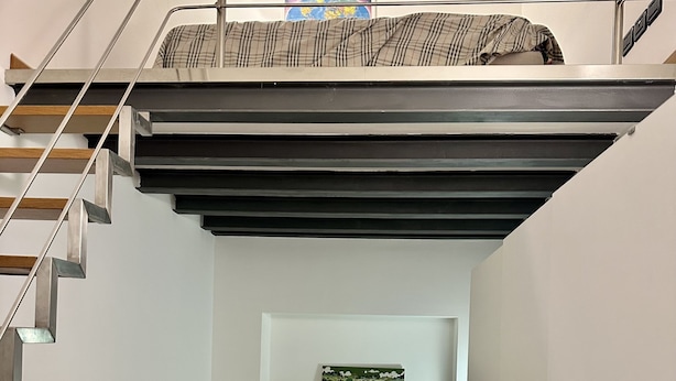 Un dormitorio pequeño con una cama litera, un escritorio y una estantería con un cuadro de paisaje.