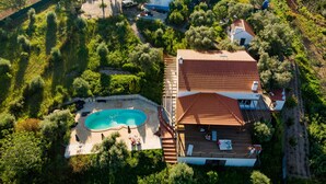 An aerial view of a property with a swimming pool, a deck area, and surrounding greenery.