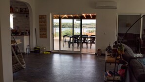 A spacious living area with a view of a lake, a wooden deck, and a sliding glass door leading to an outdoor seating area.
