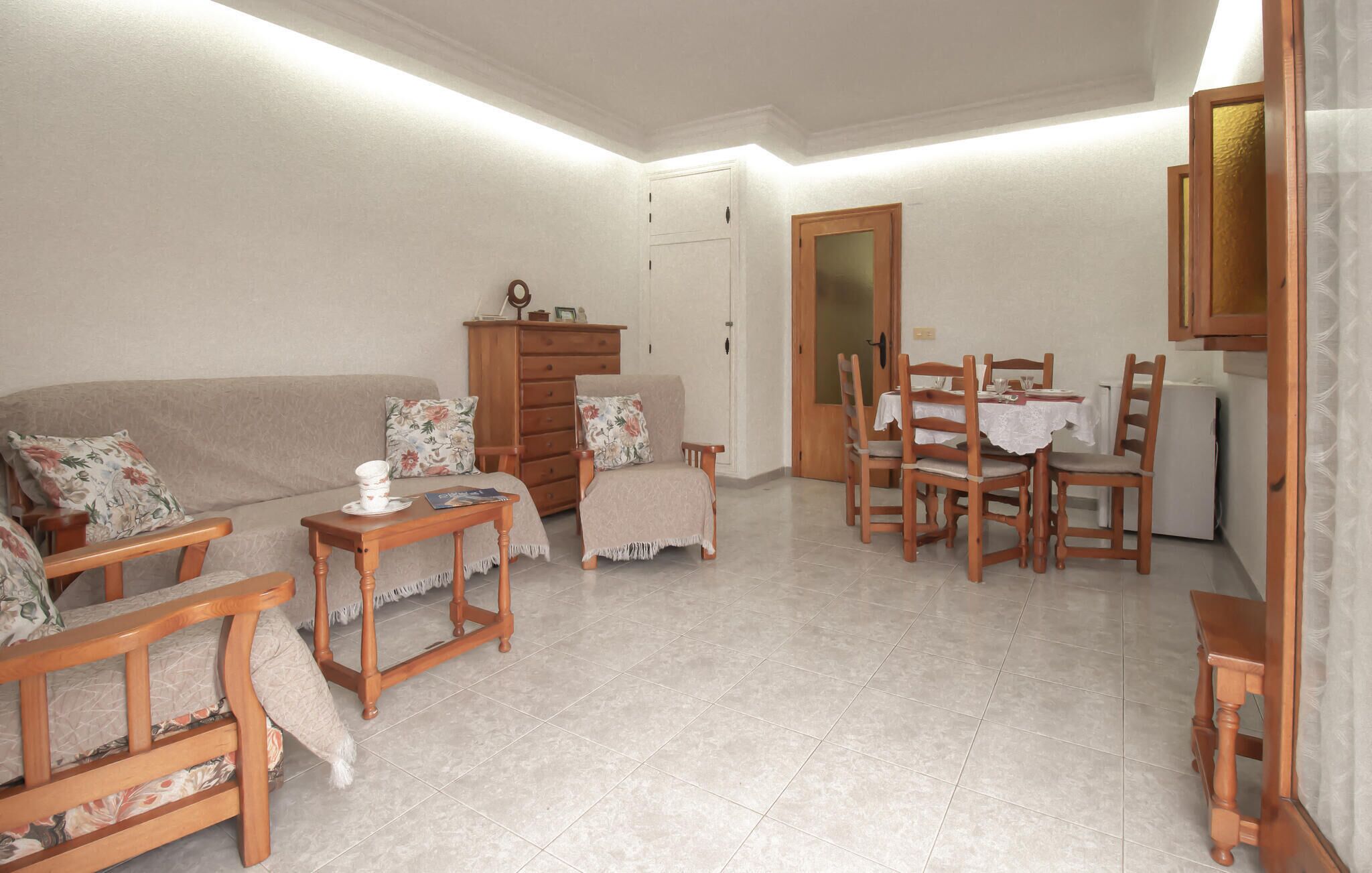 A living room with a sofa, wooden chairs, a dining table, and a cabinet.