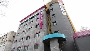 A multi-story hotel with a prominent sign, a curved entrance, and a staircase leading to the entrance. - NJ Hotel (Pyeongtaek)