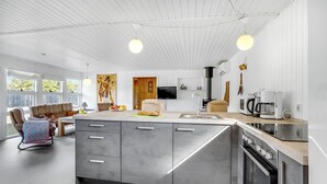Ett modernt kök med en central köksö, inbyggda vitvaror och en matplats med soffa och stolar.
