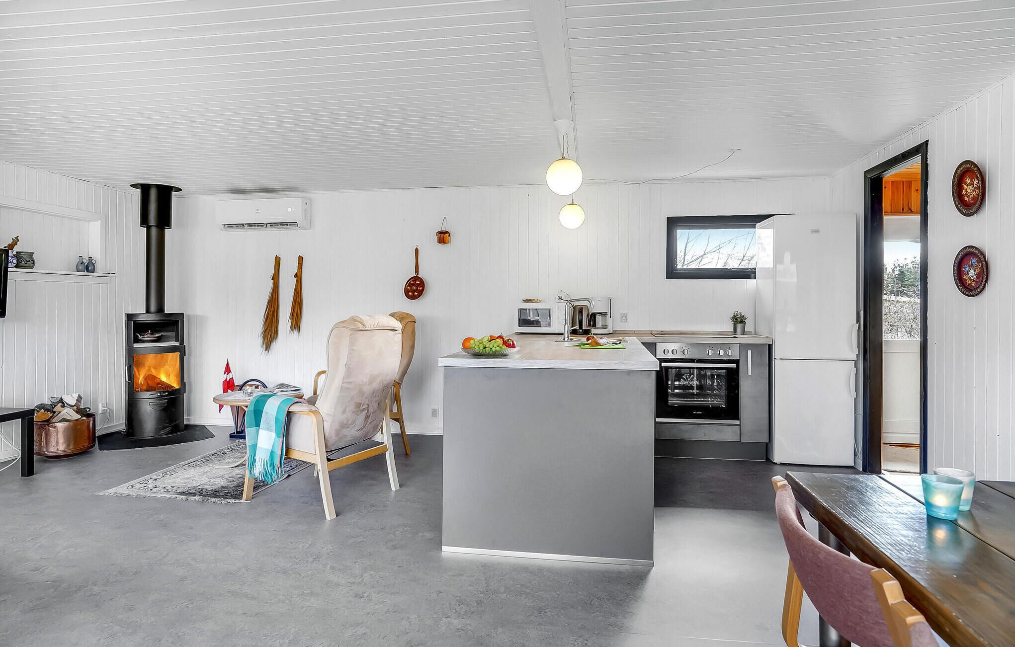 Une cuisine moderne dotée d’un îlot central, d’une cuisinière intégrée et d’un coin repas avec une table et des chaises en bois.