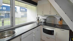 Eine kompakte Küche mit Spüle, Geschirrspüler von Bosch, Kaffeemaschine und Mikrowelle.